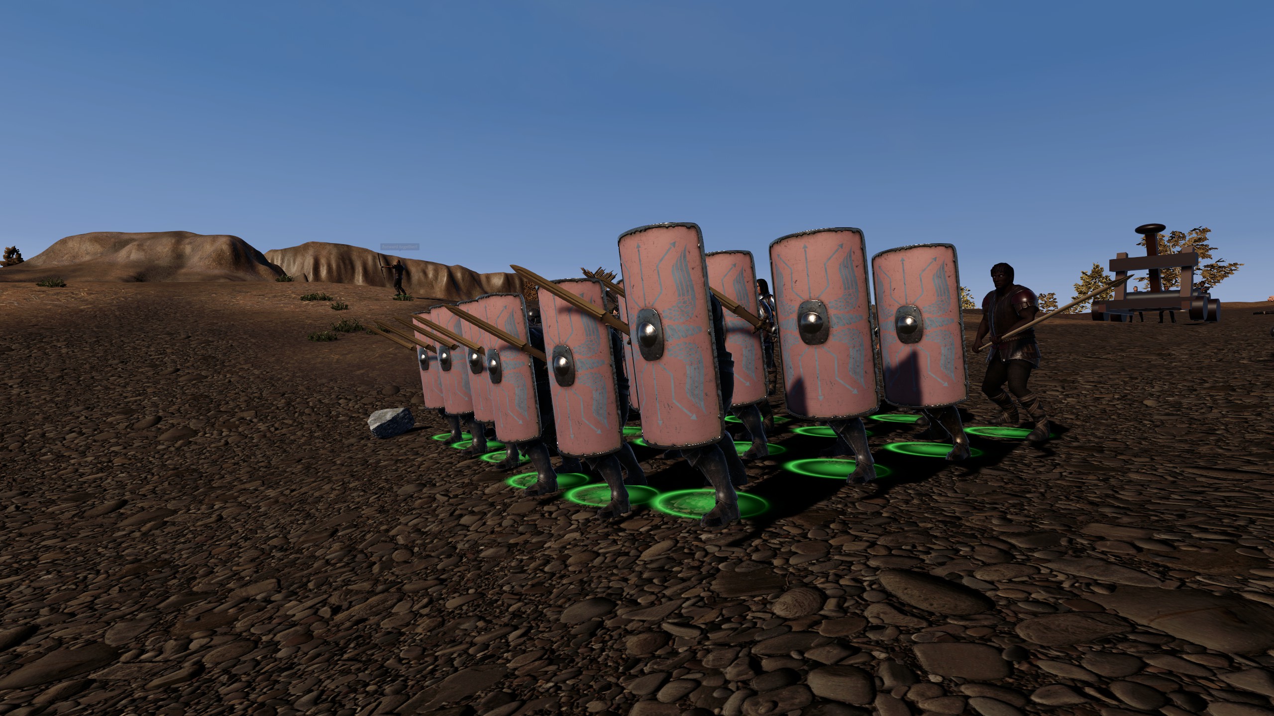A close view of soldiers advancing behind tall shields beside siege equipment in Mortalis
